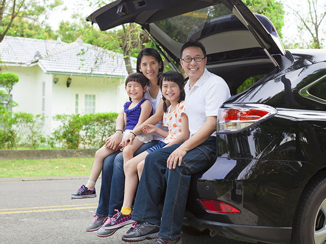 車に腰掛ける笑顔の4人家族